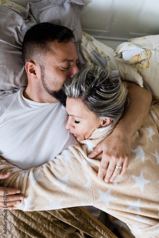 Husband and wife sleeping together in one bed - in hug