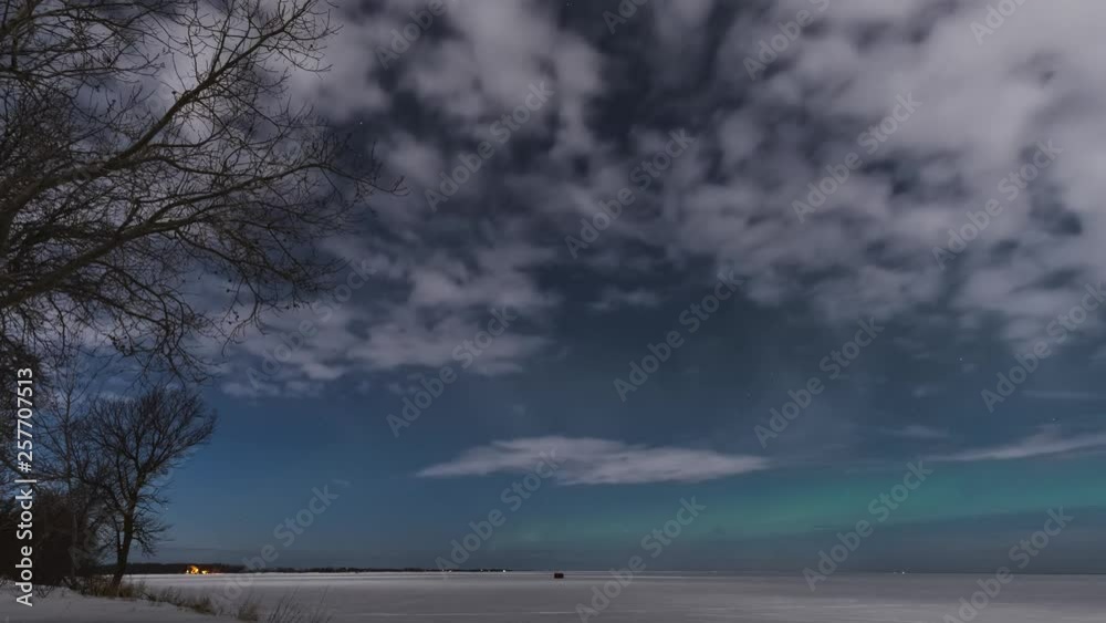 Time-lapse of moonlit clouds blowing over a snow covered lake with aurora dancing in a starry sky. Time-lapse of moonlit clouds blowing over a snow covered lake with aurora dancing in a starry sky.
