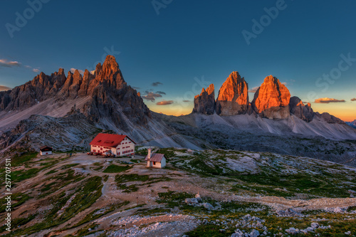 Tre Cime and rifugio hut at sunrise in summer in Dolomites, Italy.