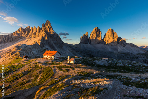 Tre Cime and rifugio hut at sunrise in summer in Dolomites, Italy.