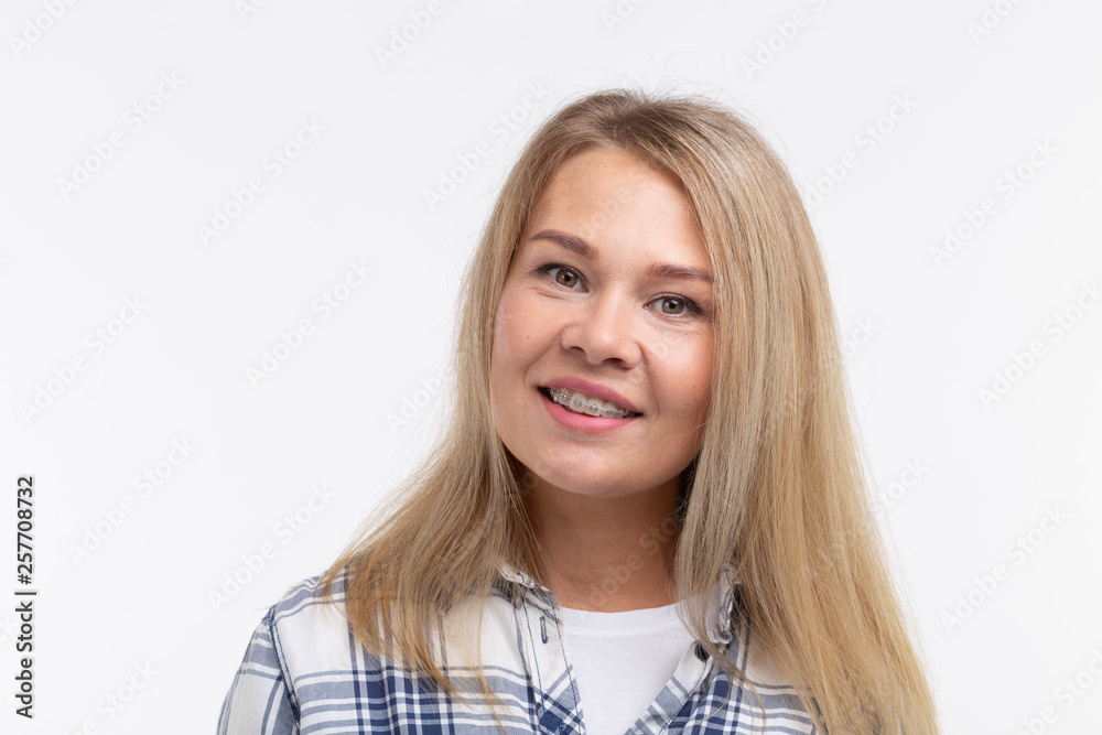 Teeth health, dentistry and bite correction - Happy smiling woman with braces on white background Teeth health, dentistry and bite correction - Happy smiling woman with braces on white background