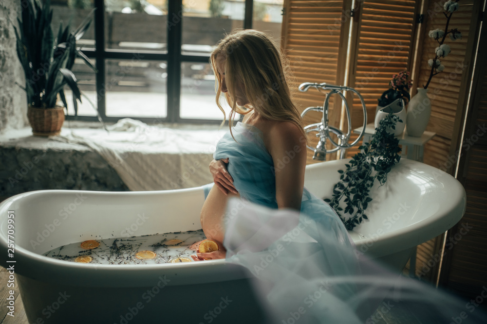 Pregnant woman takes a bath with milk, lavender herbs and orange slices ...