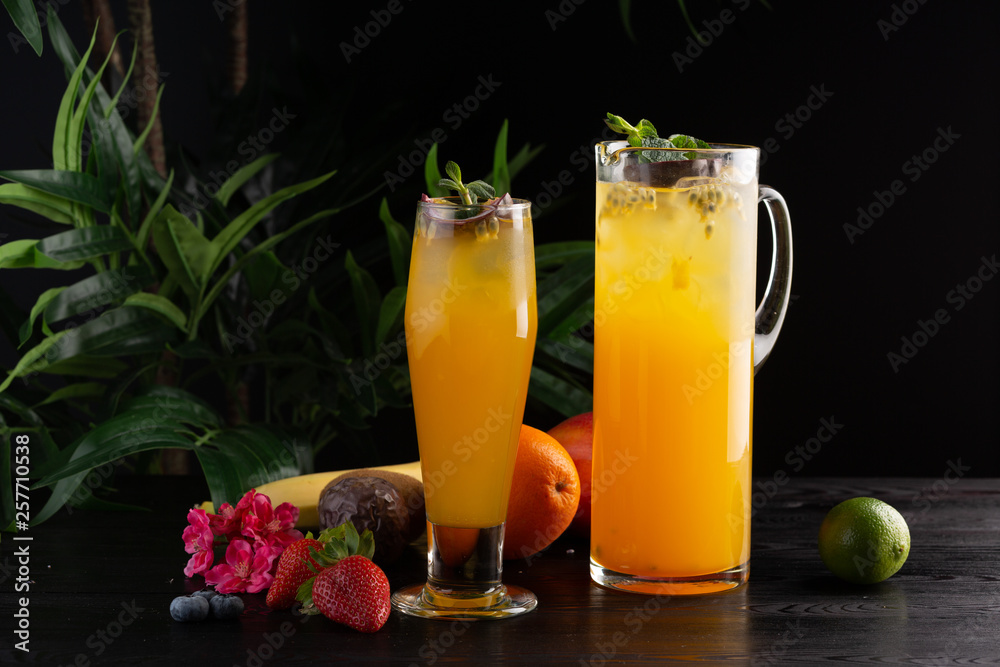 Mango lemonade - passion fruit in a jug and a glass and fruit on a dark wooden background Mango lemonade - passion fruit in a jug and a glass and fruit on a dark wooden background