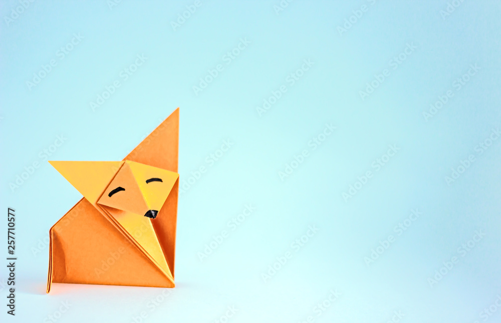 Orange fox from paper origami. Origami toy on a plain background Orange fox from paper origami. Origami toy on a plain background