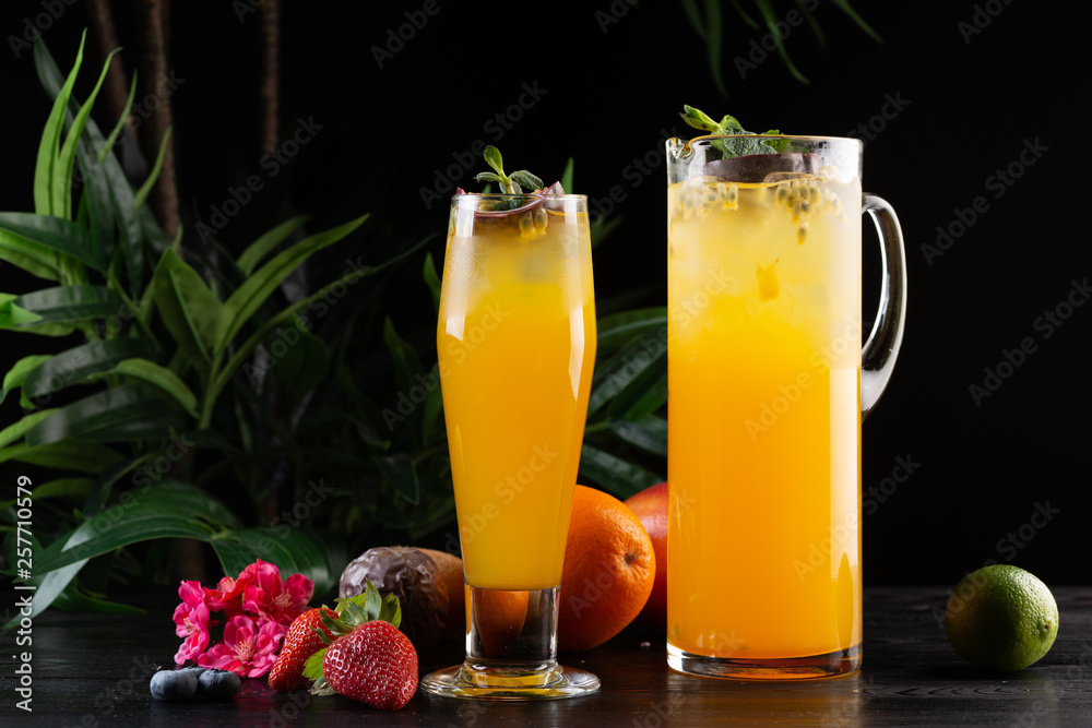 Mango lemonade - passion fruit in a jug and a glass and fruit on a dark wooden background Mango lemonade - passion fruit in a jug and a glass and fruit on a dark wooden background