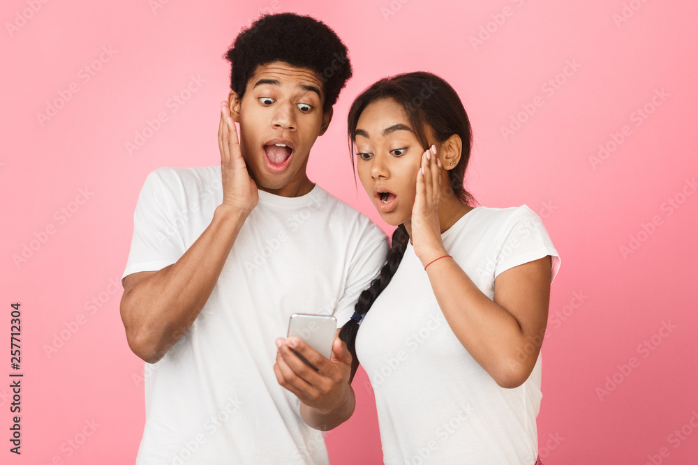 Shock content. Couple using smartphone, pink background Shock content. Couple using smartphone, pink background