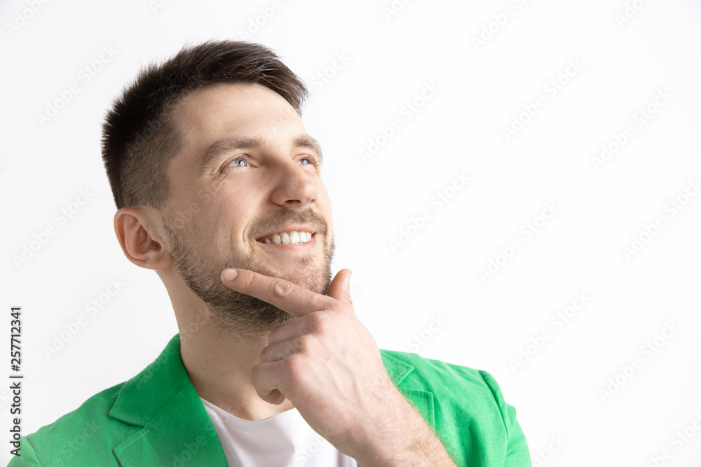 Looking for the best moment. Young dreaming smiling man is waiting for chanses isolated on gray background. Dreamer at studio in white T-shirt Looking for the best moment. Young dreaming smiling man is waiting for chanses isolated on gray background. Dreamer at studio in white T-shirt