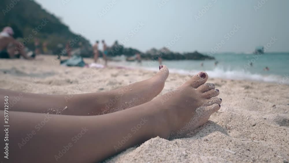 close view woman with accurate pedicure relaxes lying on warm sand near turquoise ocean under blue sky close view woman with accurate pedicure relaxes lying on warm sand near turquoise ocean under blue sky