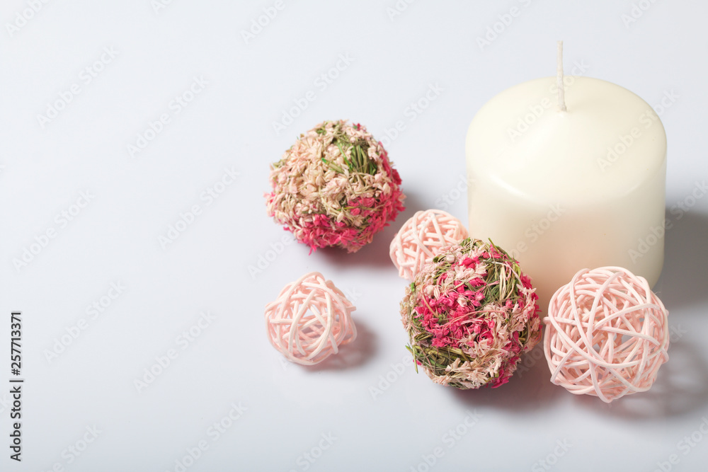 Candles white in color among the decorative balls, woven from natural materials. On a white background.