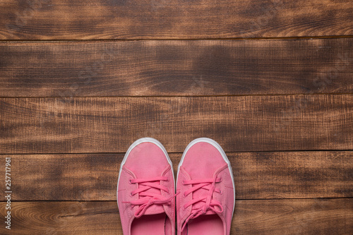 Pink sneakers on wooden background.