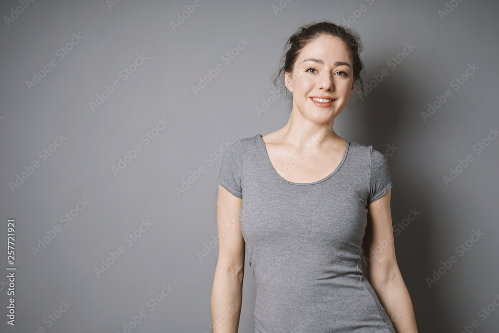 happy young woman with bright face and beaming smile against gray background with copy space happy young woman with bright face and beaming smile against gray background with copy space