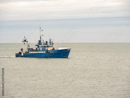 Small single fishing boat at the open sea with scenic sky.