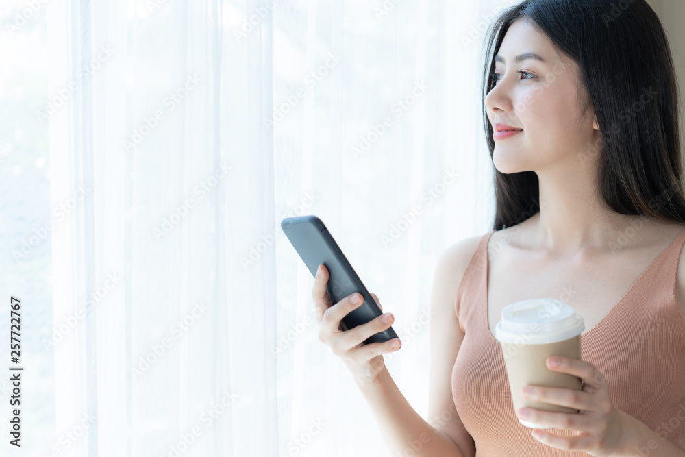 Beautiful cute girl Asian woman playing a smart phone in the morning white bedroom - lifestyle female at home Beautiful cute girl Asian woman playing a smart phone in the morning white bedroom - lifestyle female at home