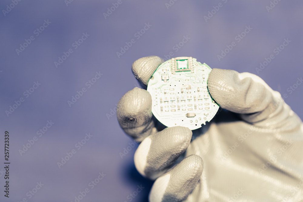 Circular electronic integrated circuit board in developer 's hand on blue background, artificial intelelligence development concept.