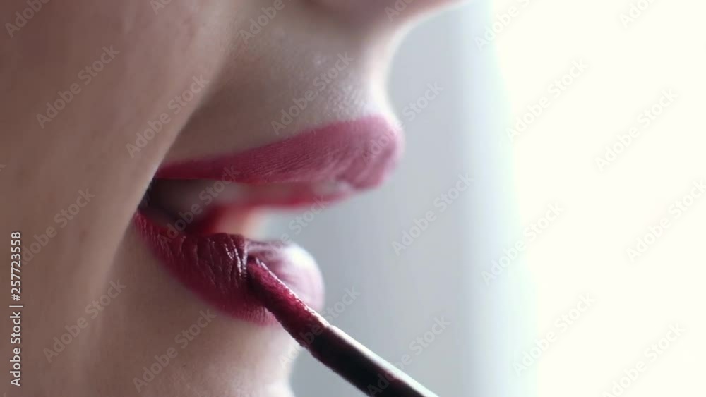 Woman putting on lipstick, macro shot, close up