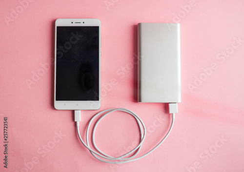 White smart phone charger with charger power bank on pink background