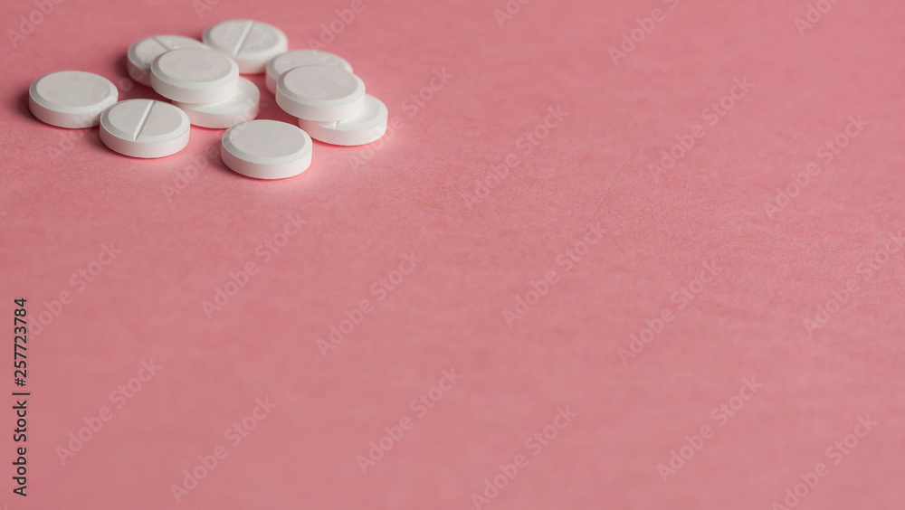 White pills on a pink background. Place for text on the left. White pills on a pink background. Place for text on the left.