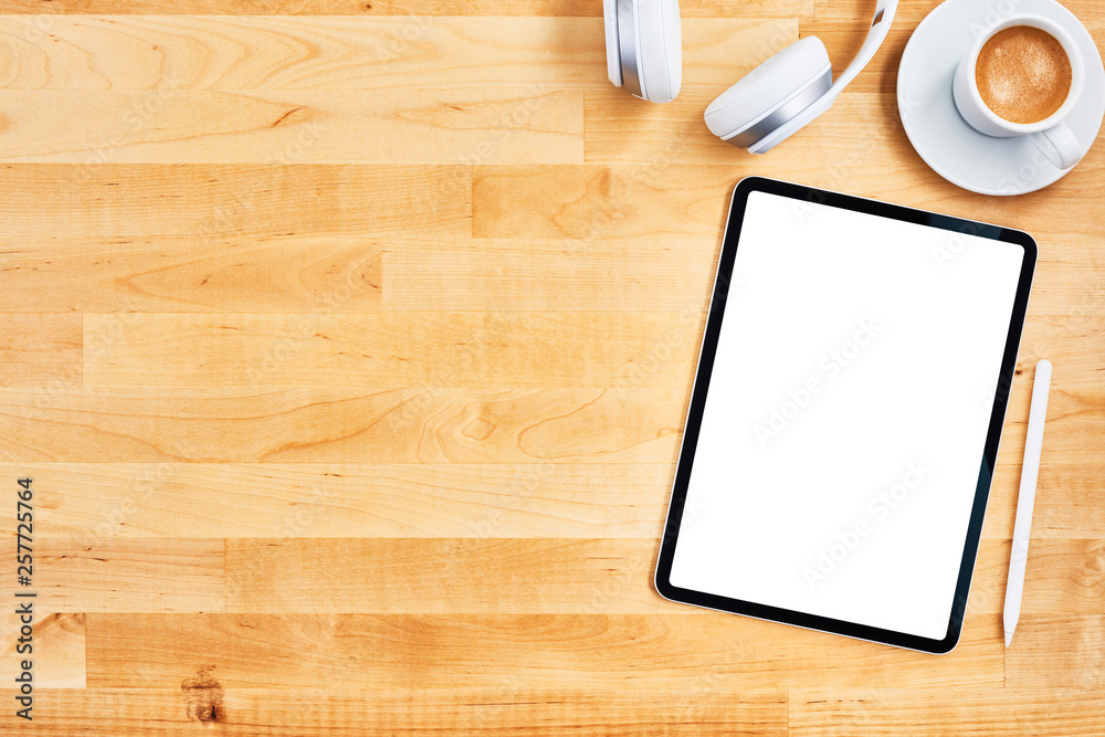 Digital tablet with blank white screen, pen, wireless headphone and cup of coffee on wooden office desk. Top view. Copy space for text or design. Flat lay. Digital tablet with blank white screen, pen, wireless headphone and cup of coffee on wooden office desk. Top view. Copy space for text or design. Flat lay.