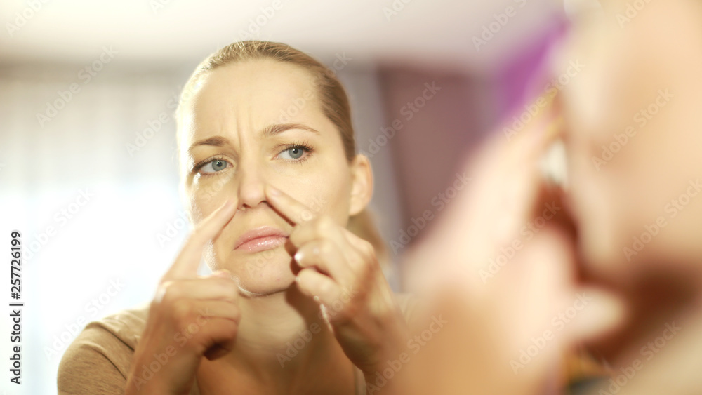 the girl looks in the mirror, dissatisfied with the appearance, pulls the skin. Ugly, aging skin. Allergy to cosmetics, fear of aging, circles under the eyes, wrinkles. Low self-esteem, dysmorphic dis the girl looks in the mirror, dissatisfied with the appearance, pulls the skin. Ugly, aging skin. Allergy to cosmetics, fear of aging, circles under the eyes, wrinkles. Low self-esteem, dysmorphic dis