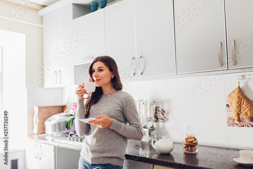 Woman pouring tea into ceramic cup at table