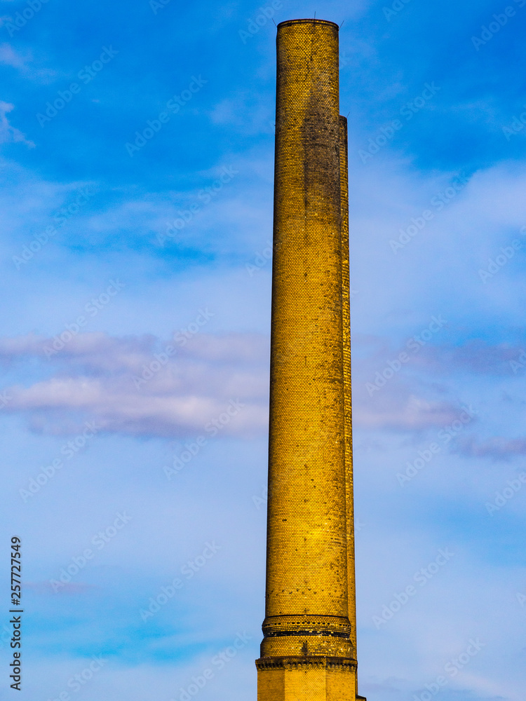 Schornstein aus gelbem Ziegelwerk vor blauem Himmel