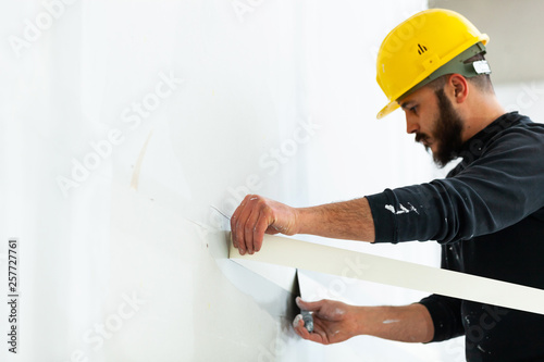 worker plastering gypsum board wall.