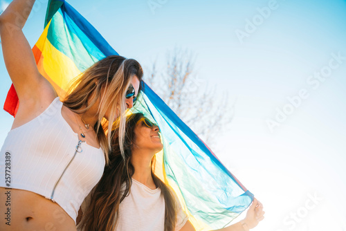 Couple lesbian woman with gay pride flag on the street