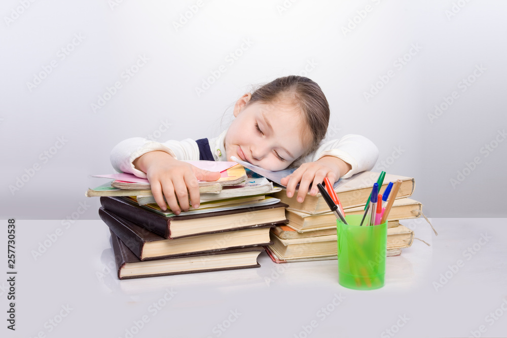 Girl doing homework. The child was tired of congestion at the school. big burden on students. overloaded child Girl doing homework. The child was tired of congestion at the school. big burden on students. overloaded child