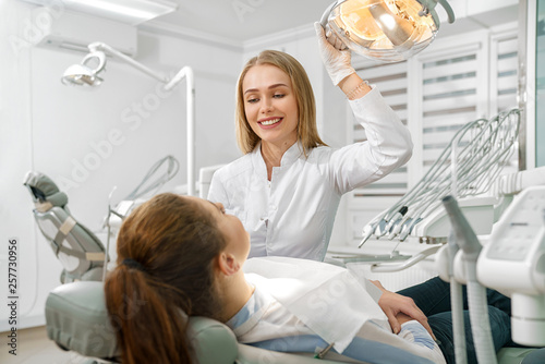Female dentist talking with patient lying on dental chair