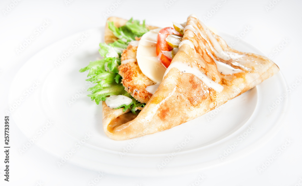 Thin delicious pancake with meat steak, cheese, tomato and greenery on white Thin delicious pancake with meat steak, cheese, tomato and greenery on white