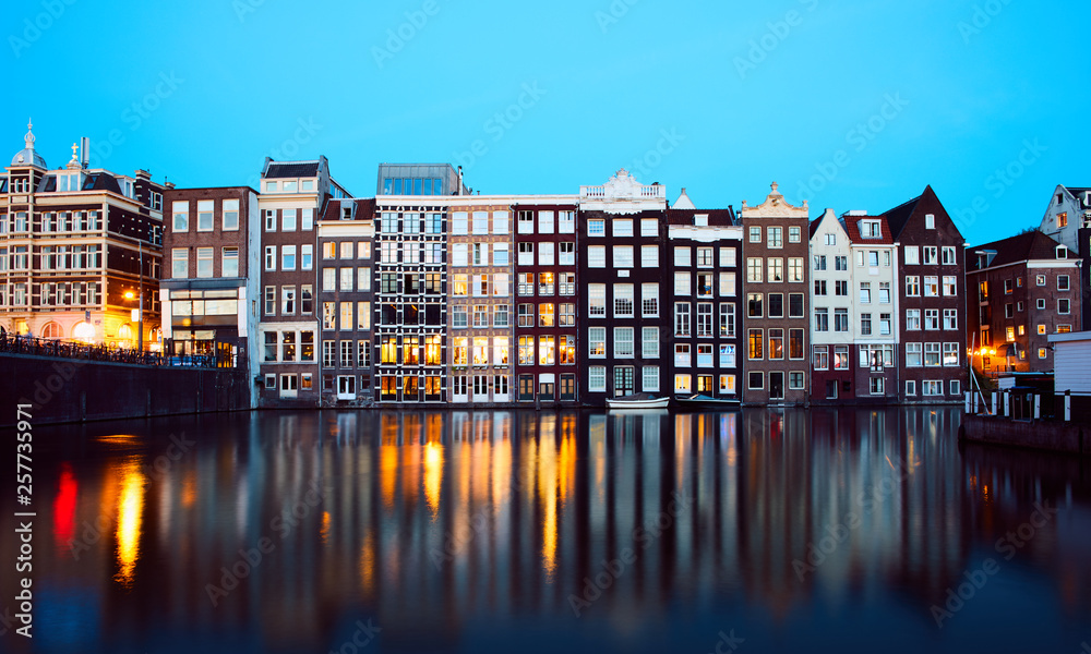 Iconic Damrak Amsterdam street waterfront at the evening shot with long exposure during sunset