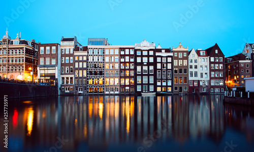 Iconic Damrak Amsterdam street waterfront at the evening shot with long exposure during sunset