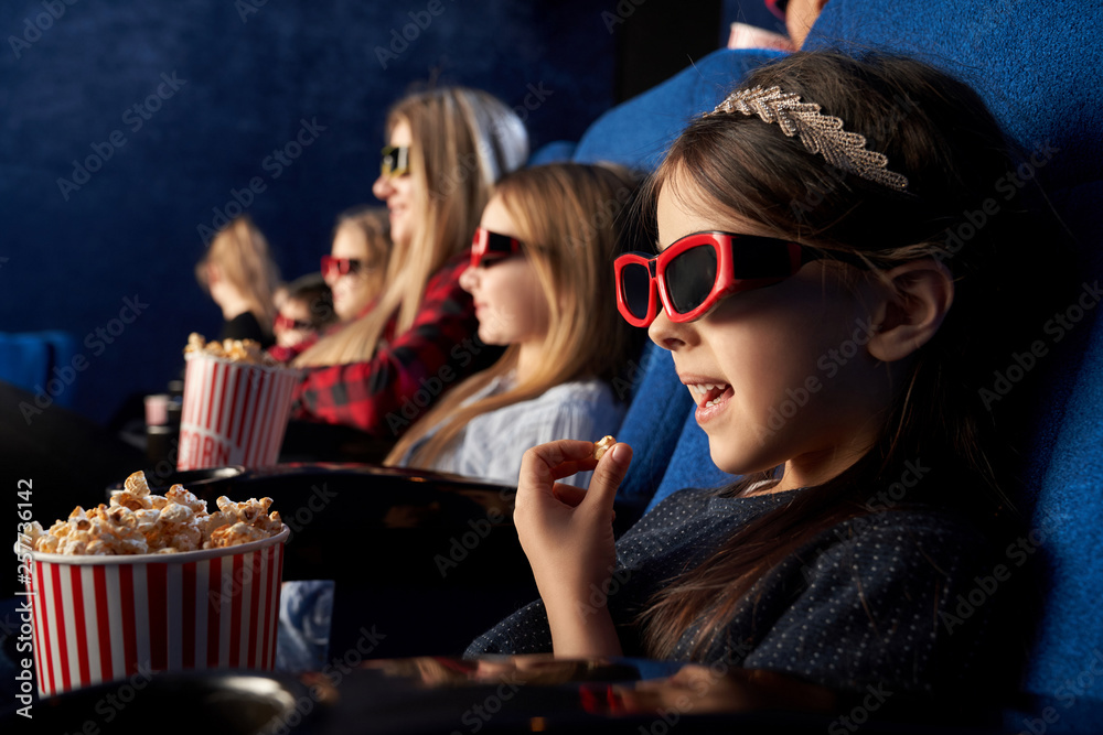 Little girl eating popcorn, watching cartoon in cinema. Little girl eating popcorn, watching cartoon in cinema.