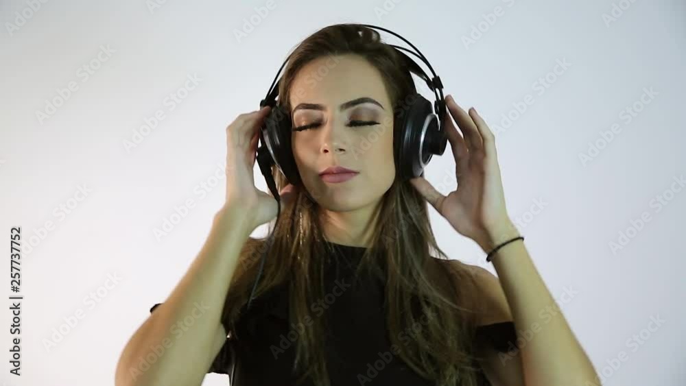 Young sexy woman or girl dj on pretty sexy face in dark shirt with musical stereo headphones or headset. Sexy girl with headphones. In the studio girl listening to music, keep the sexy hair. Flirting. Young sexy woman or girl dj on pretty sexy face in dark shirt with musical stereo headphones or headset. Sexy girl with headphones. In the studio girl listening to music, keep the sexy hair. Flirting.