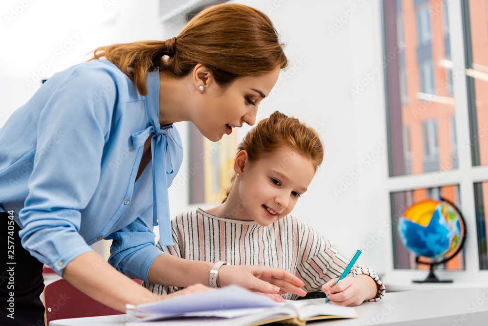 Teacher in blue blouse explaining lesson to pupil in classroom Teacher in blue blouse explaining lesson to pupil in classroom