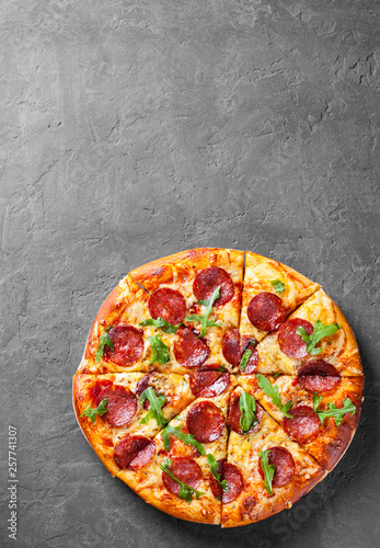 Pepperoni Pizza with Mozzarella cheese, salami, Tomato sauce, pepper, Spices and Fresh arugula. Italian pizza on Dark grey black slate background