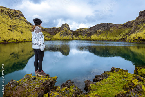 Girl teenager is staying in the border of the pond in the crater Tjarnargigur, one of most impressive craters of Lakagigar volcanic fissure area in Southern highlands of Iceland. © sasha64f