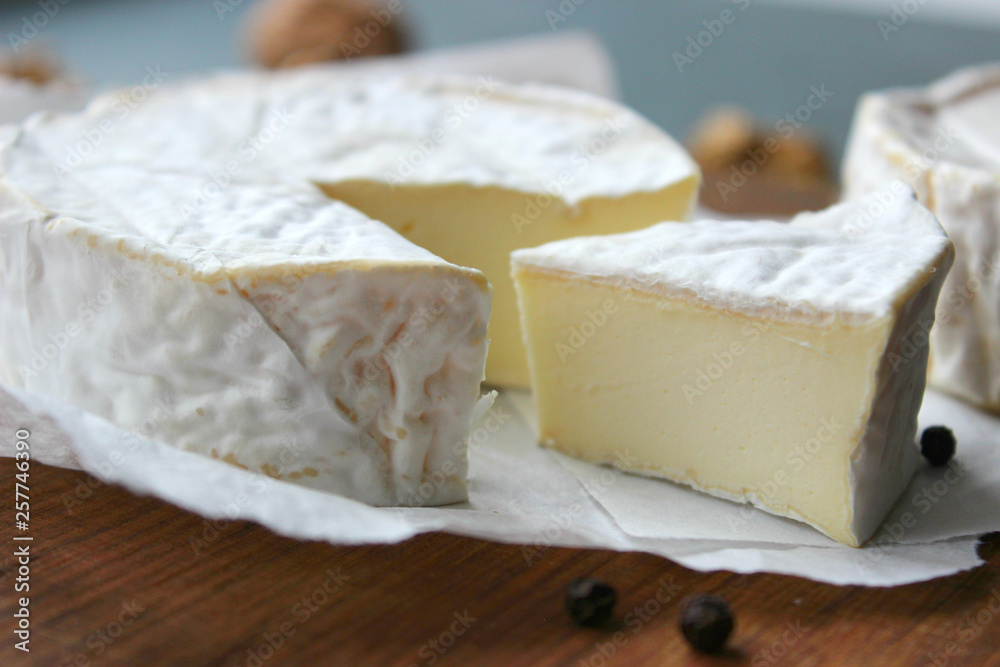 Camembert cheese. Farm products, rustic cheese. Natural cheese, round head of cheese with Camembert mold, cut on a wooden Board surrounded by fragrant spices. Cheese plate for gourmets.