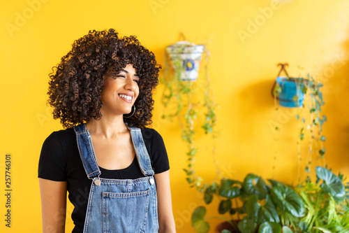 Pretty girl with curly hair and yellow background with pots and flowers photo