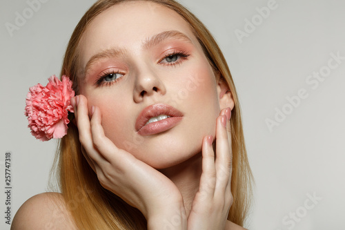 Close up portrait of dreamy blonde girl with trendy makeup touching her face