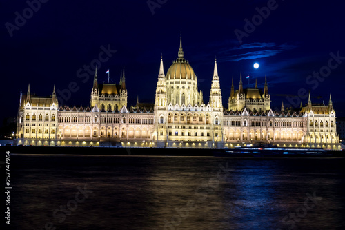 View of the Budapest Parliament at dusk with the Moon on its roofs at the blue hour, Hungary © ManryWorld