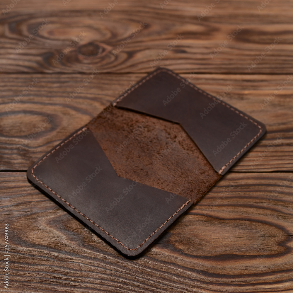 Handmade brown leather cardholder on wooden background. Stock photo with blurred background. Handmade brown leather cardholder on wooden background. Stock photo with blurred background.