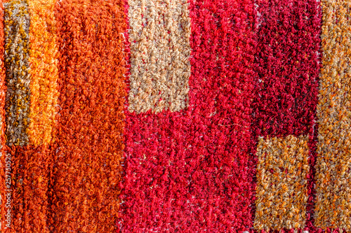Fragment de tapis artisanal, texturé, coloré, rouge, orange, jaune. e