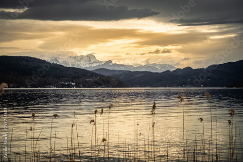 Sunset over lake Wörthersee with some reed and mountain Pyramidenkogel