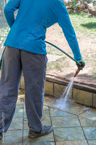 Housekeeper washes external verandah with water image with copy space in portrait format