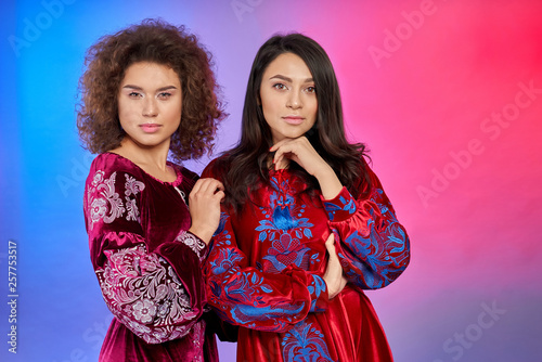 Cheerful brunettes posing in atlas embroidered dresses.