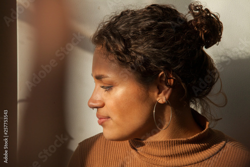 Fotografie Close-up of serious thoughtful woman looking away while sitting against wall at