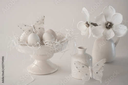 white romantic Easter scene  cake stand with eggs  porcelain pottery  watering can  vase   flowers  butterfly. against white background 