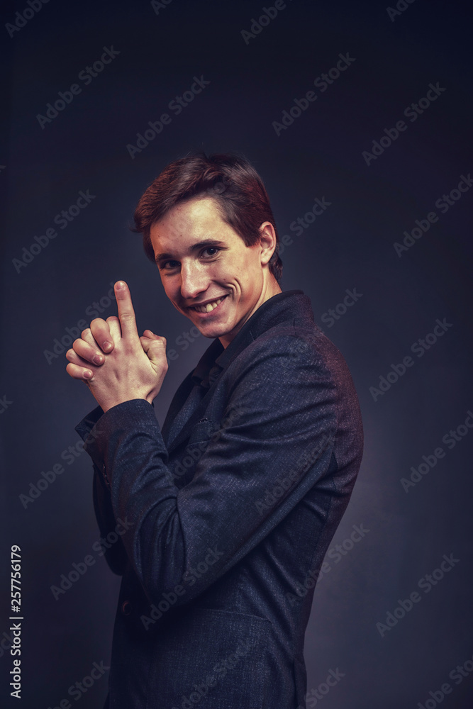 Portrait of an expressive, stylish, young man in a strict suit in orange tones with a smoky background