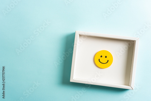 Concept of well done, feedback, employee recognition award. happy yellow smiling cartoon face frame on blue background. photo